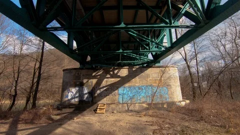 Forward dolly moving tilt up under iron railway bridge pillar Stock Footage 123927012