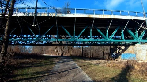 Forward dolly moving tilt up under iron bridge steel frame on sunny winter day Stock Footage 123927925