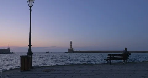 Forward Dolly Shot Of A Harbour With Lighthouse And Person Sitting On A Bench Stock Footage 119699311