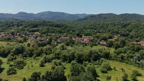 Forward drone flight over treetops towards a mountain village 스톡 동영상 344628950