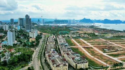 Forward drone flight scanning modern city blocks with Ha Long Bay background 4K Stock Footage 336650860