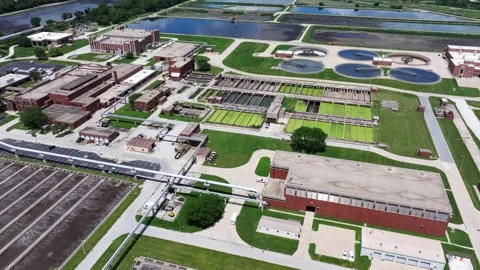 Forward drone shot above a water reclamation facility revealing bright green Stock Footage 338102954