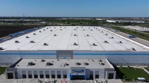 Forward drone shot descending from rooftop level above a large Amazon Stock Footage 339025358
