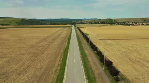 Forward Drone Shot Over Rural Road with Cars, Farmland and Village Surrounde Stock Footage 314226392