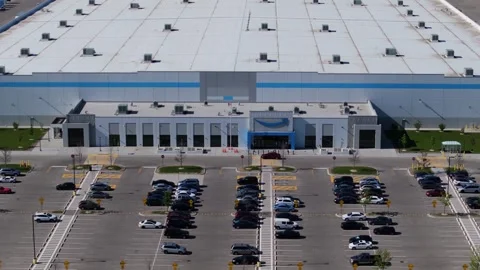 Forward drone shot toward the main entrance of an Amazon fulfillment center Stock Footage 338158139