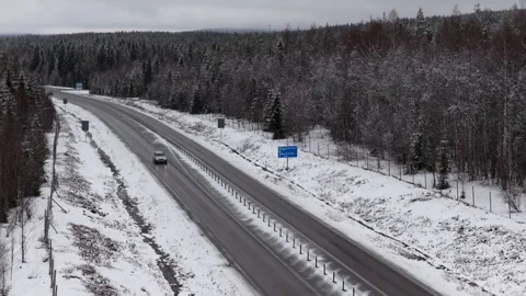 Forward drone view of snowy highway near Armsjön with Sundsvall sign, Sweden Видео 333673814
