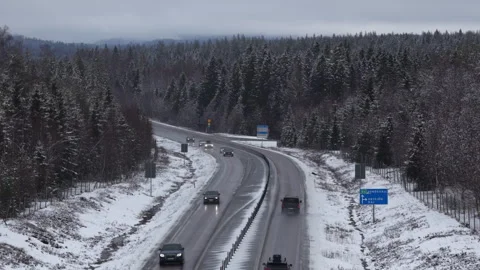 Forward drone view of snowy highway near Armsjön with Sundsvall sign, Sweden Видео 333682113