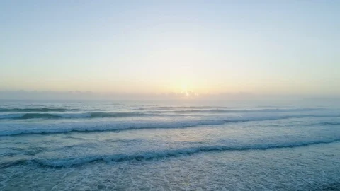 Forward flight low over water facing coming ocean waves at sunrise Video stock 103470158