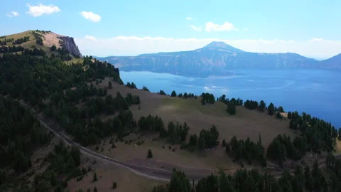 Forward flight over the cliffs edge towards deep blue Crater Lake Stock Footage 144364598