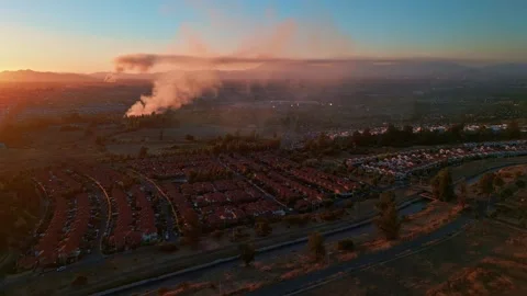 Forward flight over dense residential suburb at sunset with dramatic smoke Stock Footage 336267348