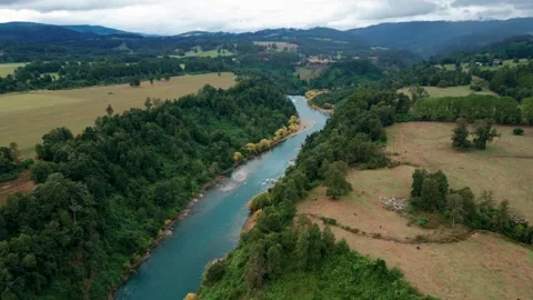 Forward flight over turquoise river winding through forest and fields. Malihue 스톡 동영상 331162013