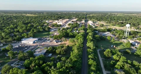 Forward flight viewing lots of trees around a small downtown area Video stock 335671471