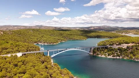 Forward moving aerial view of impressive arch bridge crossing crystal clear Stock Footage 317771573