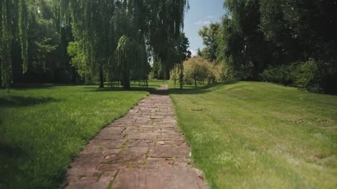 Forward moving camera along a natural stone pathway in a lush green park 스톡 동영상 326467412