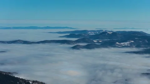 Forward moving drone shot above sea of fog and mountain terrain, delivering.. Video stock 327355052