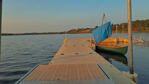 Forward Moving Shot Down A Dock Towards The Lake With Canoe Stock Footage