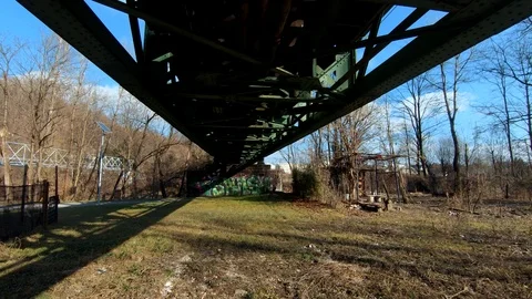 Forward moving under iron railway bridge pillar with SPLASH graffiti Stock Footage 123927633