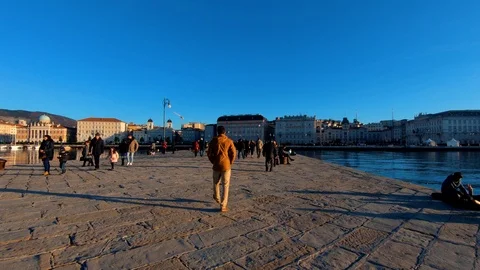 Forward moving walking on stone pier people tourists in Trieste city Stock Footage 122364630