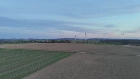 Forward rise over ploughed field toward turbine horizon Stock Footage 331214760