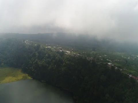 Forward through clouds, over small town and lake in Bali Indonesia. Stock Footage 80146011