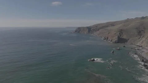 Forward tracking drone along hillside, ocean left, hill right Stock Footage 336792043