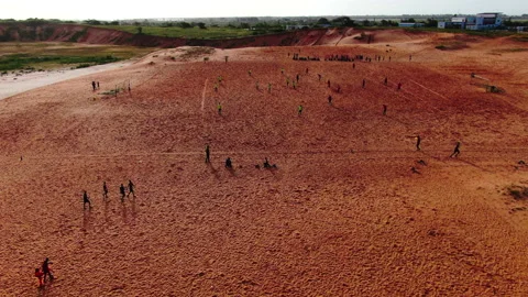 Forward tracking shot of people playing football on dirt field, Senegal Stock Footage 331991713