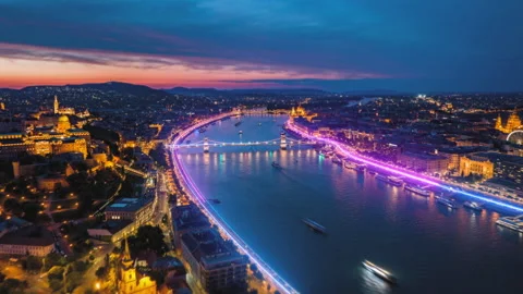 Forwards fly above Danube river calmly flowing through capital at dusk. Aerial Stock Footage 248543107