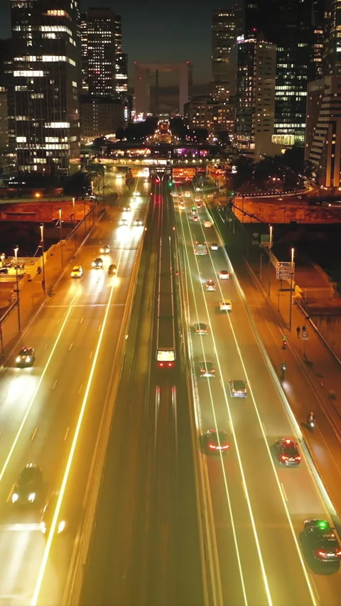 Forwards tracking of subway train driving on tracks in center of multilane road Stock Footage 323749797