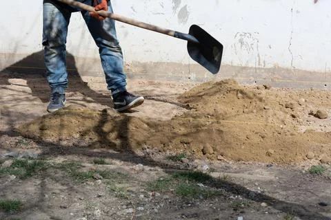 Foundation blind area preparing. An unknown worker of European appearance pou Stock Photos