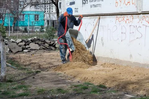 Foundation blind area preparing. An unknown worker of European appearance pou Stock Photos