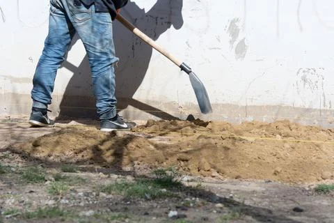 Foundation blind area preparing. An unknown worker of European appearance pou Foto stock