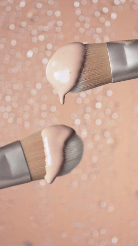 Foundation drops falling from a cosmetic brush. Vertical video Stock Footage 307304957