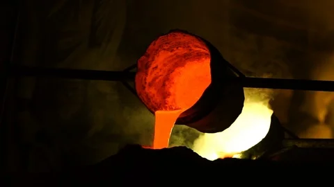 Foundry worker pouring hot molten metal into mold casting Stock Footage