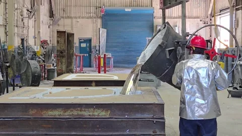 Foundry worker pouring molten metal (kirksite) into a sand mold, creating Stock Footage 332937013
