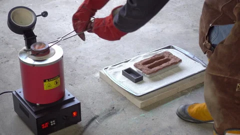 Foundry worker rotates crucible inside furnace with tongs. Stock Footage 331316402