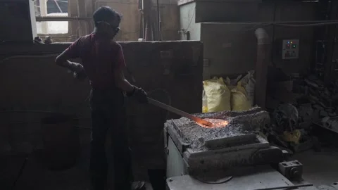 Foundry Worker Skimming the Surface of a Hot Metal Bath Stock Footage 346880313