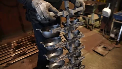 Foundry worker sorting scrap metal pieces into wooden crate on factory floor Видео 345030616