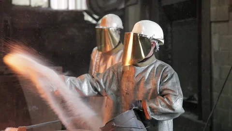 Foundry worker throwing matter on melted metal Stock Footage 231497152
