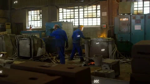Foundry workers stirring molten metal from furnace glow, heatmap showing mold Stock Footage 334321862