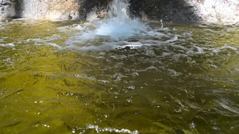 Fountain falls into a pool with yellow water of a mountain river (slow motion) Video stock 212770751