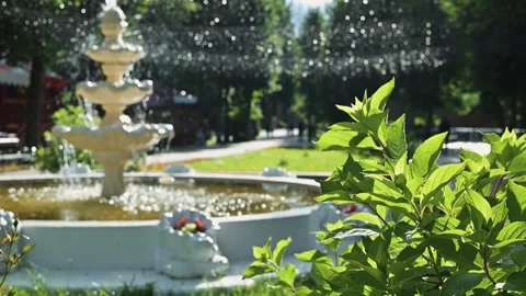 A fountain is flowing in a public area as sunlight shines down. Surrounding Stockbeeldmateriaal 344527902