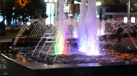The fountain, lit by multicolored lights. Stock Photos