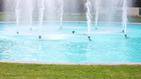A fountain with multiple water jets spraying upwards in a turquoise pool of 스톡 동영상 318831132