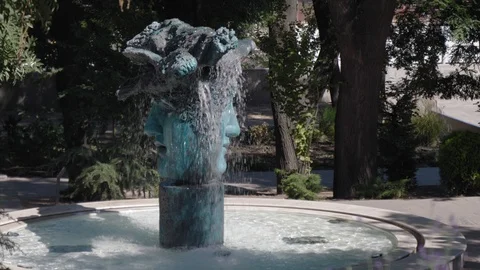 A fountain in the park in the form of a two-faced head. Stockbeeldmateriaal 115809312