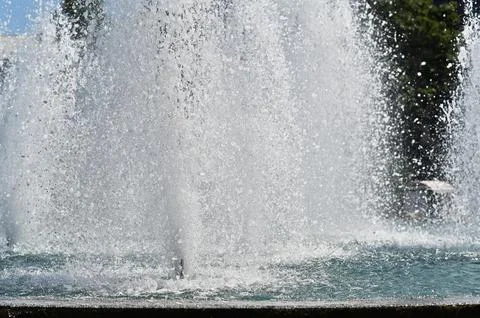 Fountain with powerful water jets creating splash effect in outdoor pool. Stock Photos