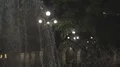 Fountain shooting water jets in air against illuminated streetlights at night HD Footage