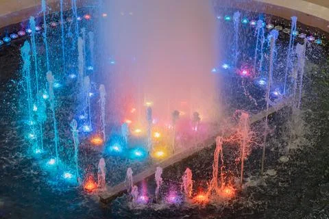 A fountain with streams illuminated by multicolor backlights. Multi-colored Stock Photos