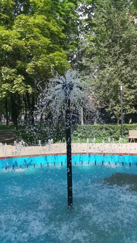 A fountain. Streams of water cascade against a backdrop of green trees. Stock Footage 328812845