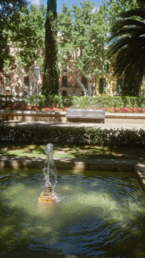 Fountain surrounded by lush greenery and colorful flowers in an outdoor par.. Stock-Footage 291002935