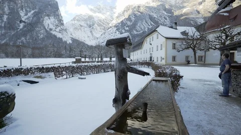 Fountain water flows into old log trough with snowy mountains Stock Footage 121011914